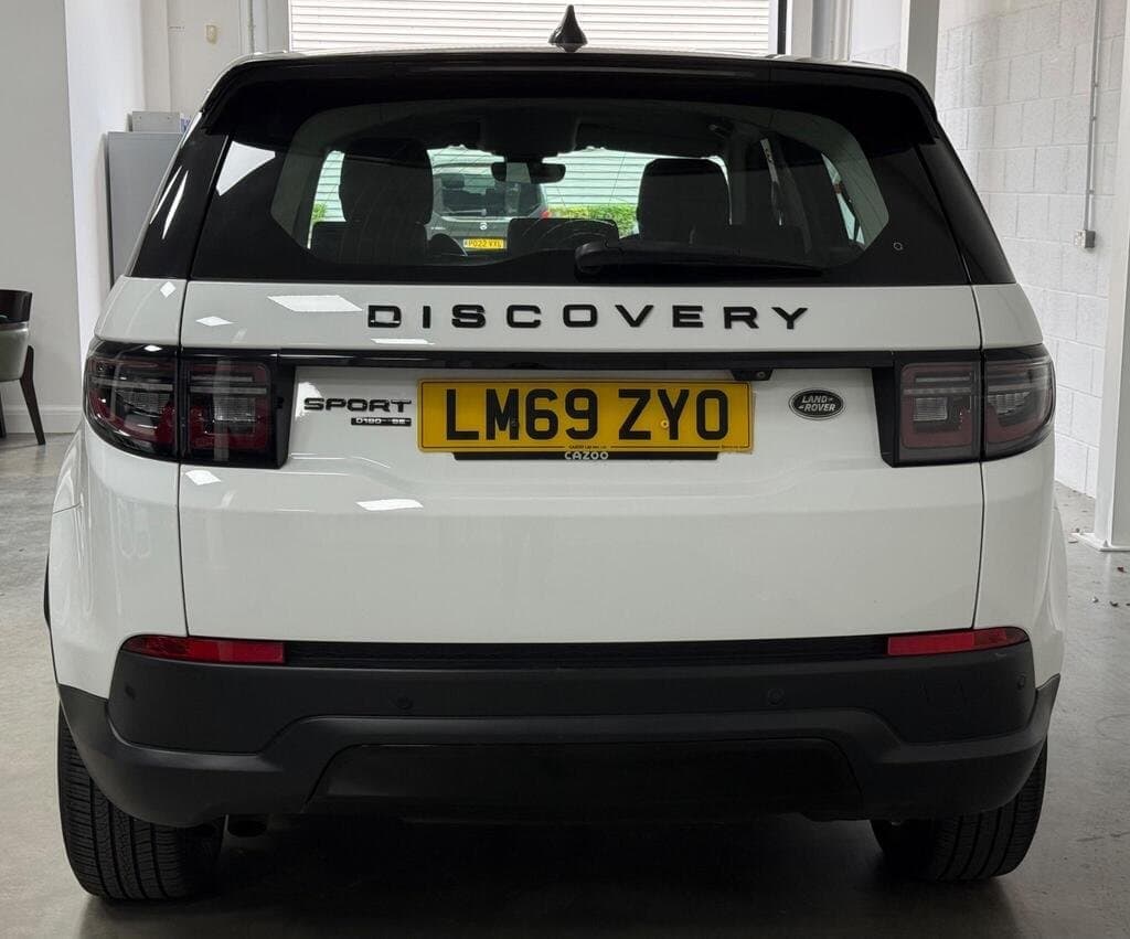 Land Rover Discovery Sport SE in Fuji White, rear three-quarter view, showroom setting